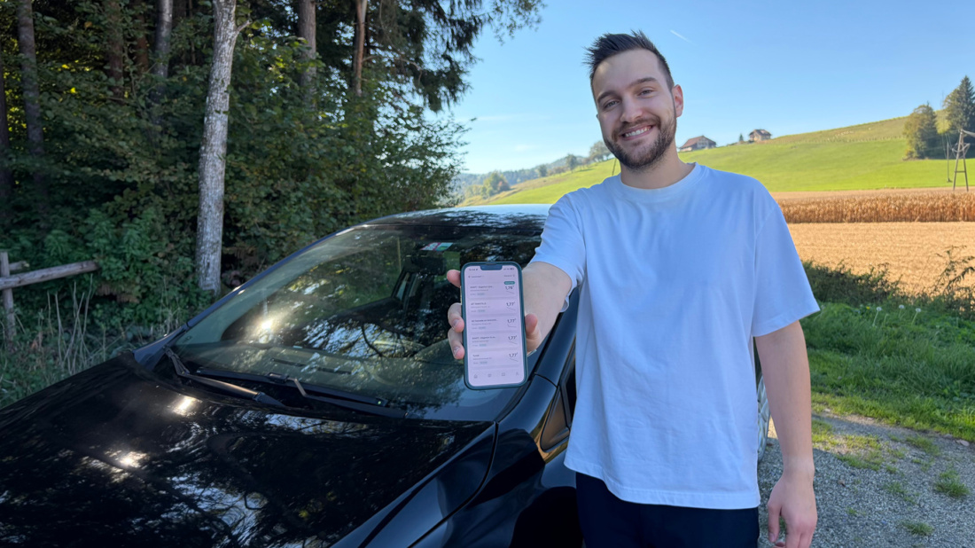 Junger Mann mit Handy in der Hand vor Auto.