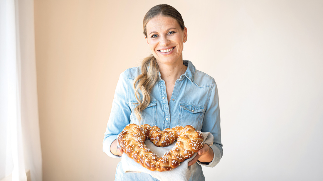 Blonde Frau mit herzförmigen Butterzopf in der Hand.